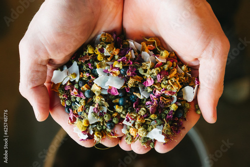 Two hands hold craft beer flavor ingredients including coconut, flowers and herbs photo