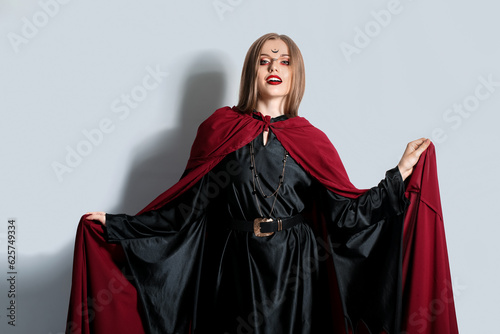 Beautiful young witch on light background