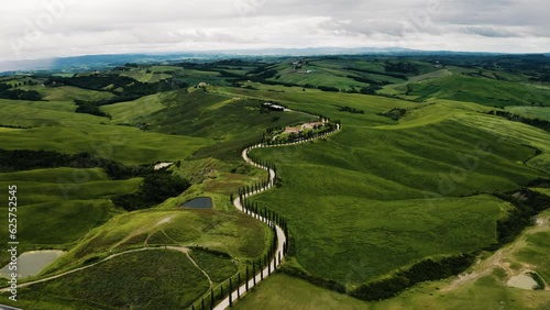 Drone shot of a winding road leading to a farmhouse in Tuscany, Italy. photo