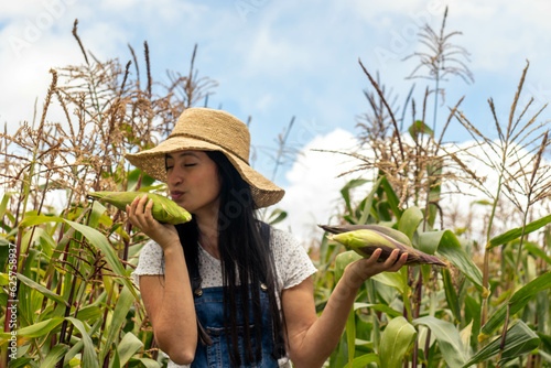 Mujer joven latina besando un choclo de felididad de la buena cosecha photo