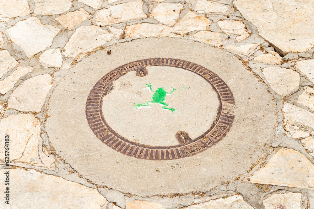 A green frog is painted on a manhole cover in the famous artists village Ein Hod near Haifa in northern Israel