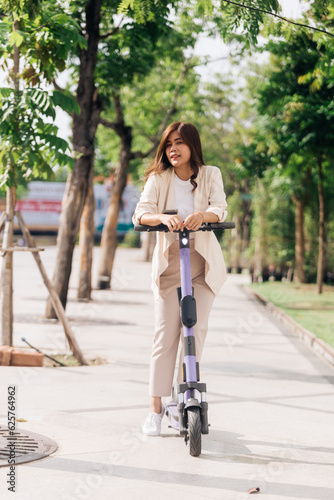 portrait of young asian woman riding electric scooter in park