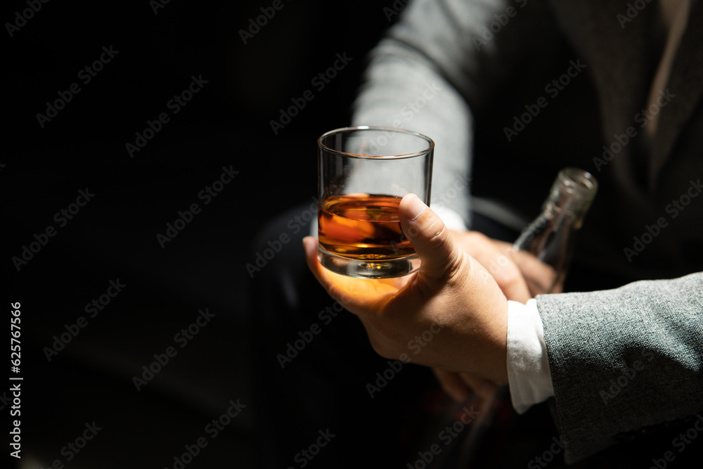 Businessman sitting and holding glass of whiskey Businessman sitting and holding glass of whiskey