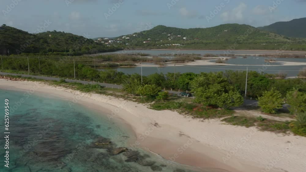 Antigua and Bermuda - 2023: aerial view Jeep drives on caribbean sandy coast surrounded by scenic nature and blue turquoise water. Road trip adventure outdoors concept Antigua and Bermuda - 2023: aerial view Jeep drives on caribbean sandy coast surrounded by scenic nature and blue turquoise water. Road trip adventure outdoors concept