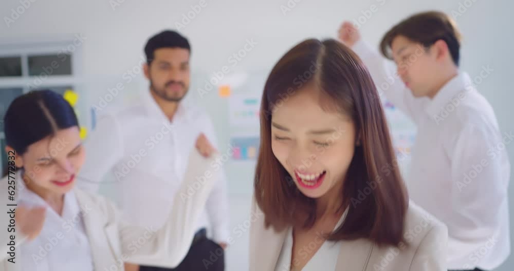 Young business asian woman enjoying and dancing with team at office. Business team dancing behind her they enjoying with work together. Young business asian woman enjoying and dancing with team at office. Business team dancing behind her they enjoying with work together.