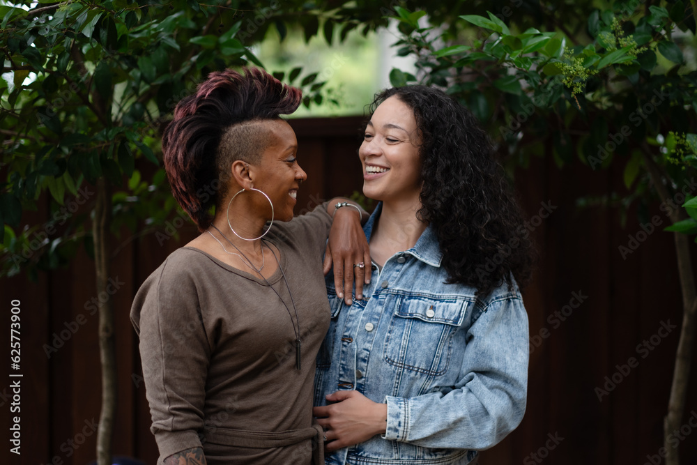 Fototapeta premium With their arms wrapped around each other, two women hug in a candid moment expressing their love, communication, and honesty with each other. They are lesbian, multiracial, and Black.