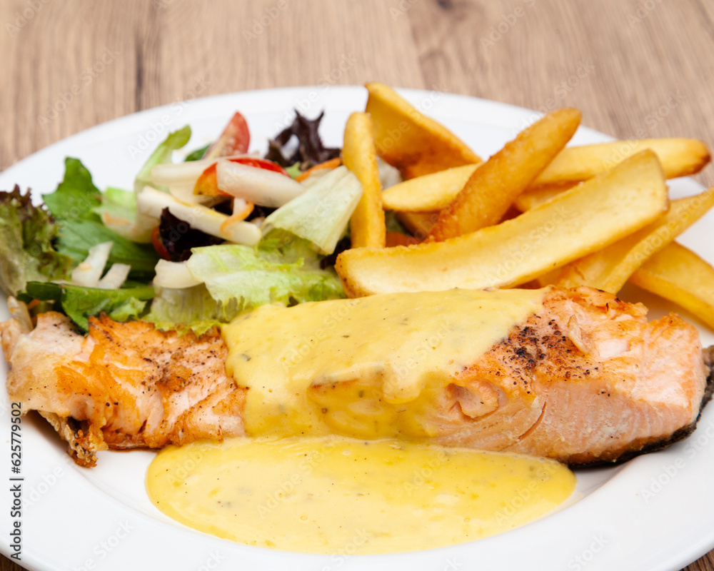 Salmon steak with fries, salad and hollandaise sauce Salmon steak with fries, salad and hollandaise sauce