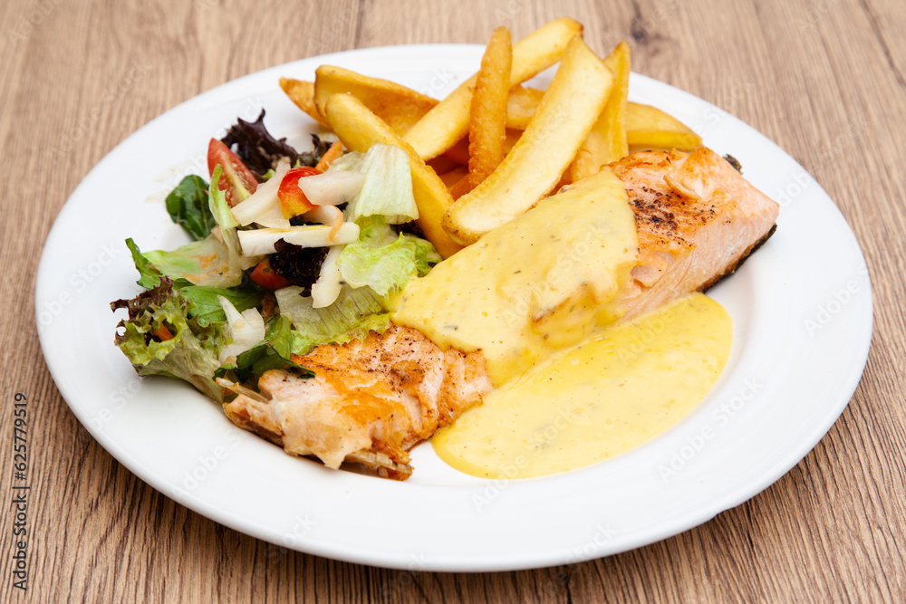 Salmon steak with fries, salad and hollandaise sauce Salmon steak with fries, salad and hollandaise sauce