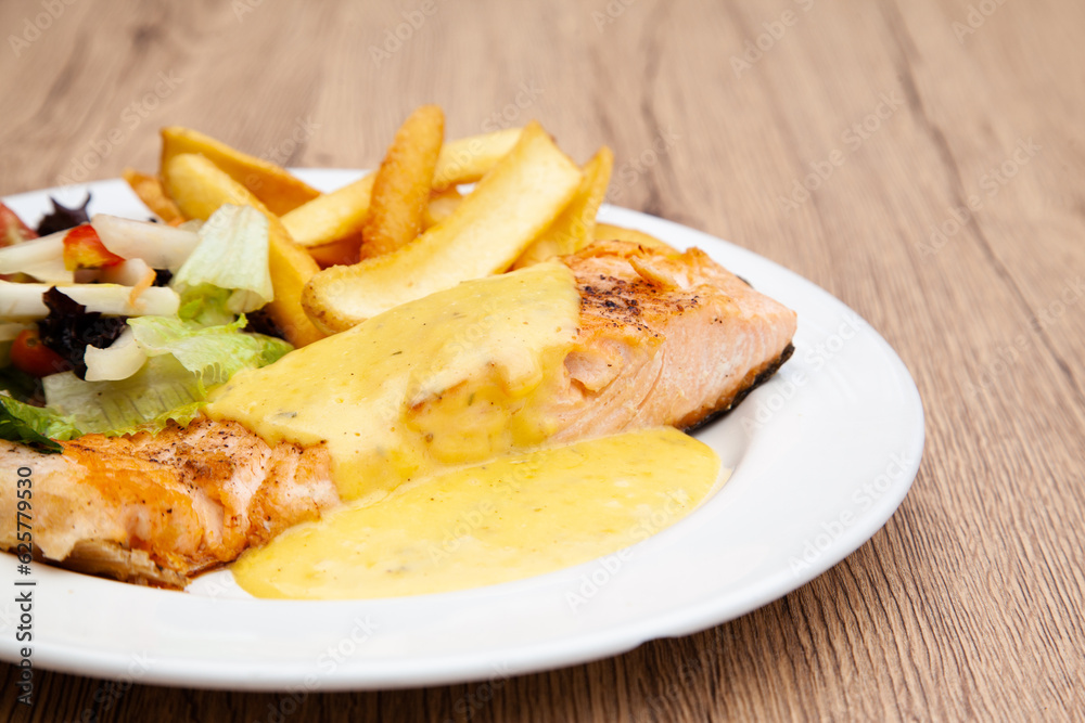 Salmon steak with fries, salad and hollandaise sauce Salmon steak with fries, salad and hollandaise sauce
