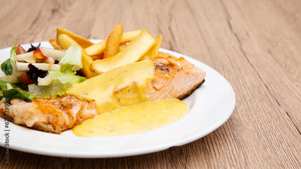 Salmon steak with fries, salad and hollandaise sauce