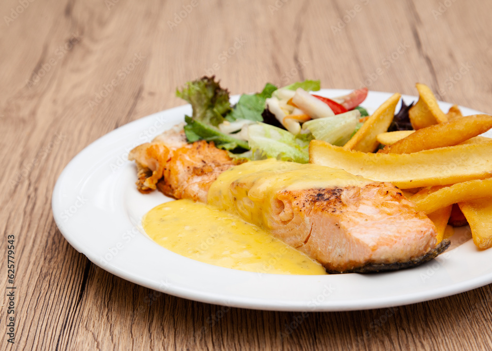 Salmon steak with fries, salad and hollandaise sauce