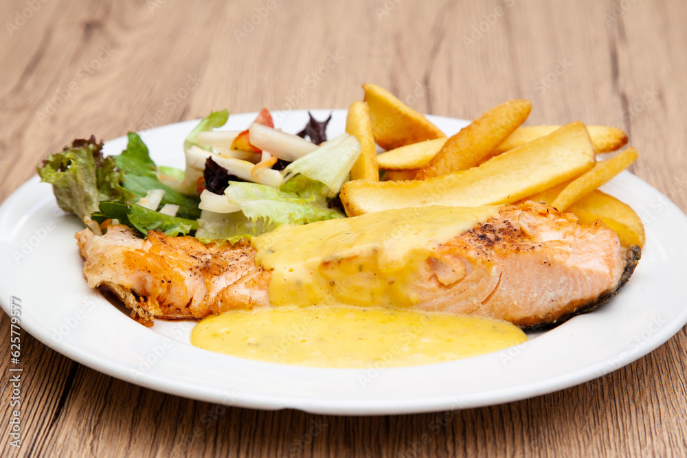 Salmon steak with fries, salad and hollandaise sauce Salmon steak with fries, salad and hollandaise sauce