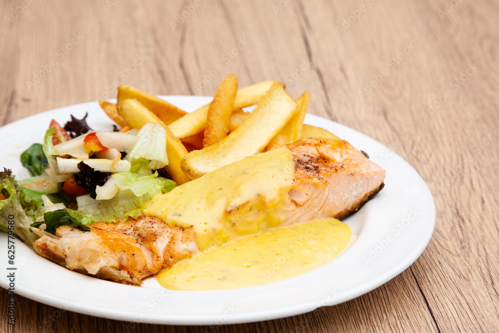 Salmon steak with fries, salad and hollandaise sauce Salmon steak with fries, salad and hollandaise sauce