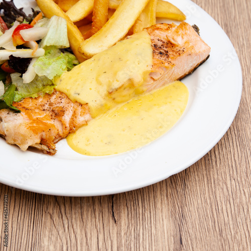 Salmon steak with fries, salad and hollandaise sauce