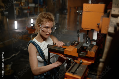 Woman wearing safety protective goggles working on milling and drilling machine