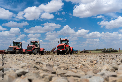 Panoramic view of a red wheeled tractor on a farm. Mechanization of agricultural work