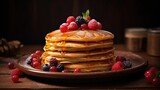 pile of pancakes with melted sweet syrup and fruit toppings with a blurred background