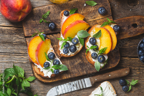 White bread sandwich with peaches, blueberries on a wooden board