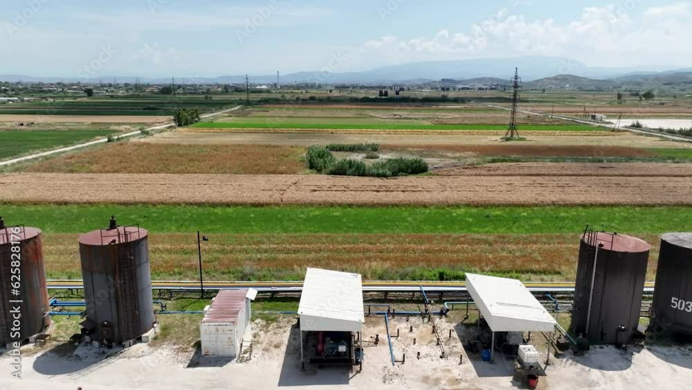 Panoramic shot of industrial oil tanks next to farming fields causing pollution Panoramic shot of industrial oil tanks next to farming fields causing pollution