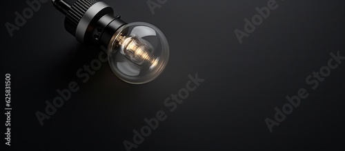 Photo of a close up of a luminous light bulb against a dark backdrop with copy space