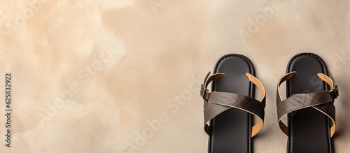Photo of a pair of brown sandals resting on a wall with ample copy space with copy space