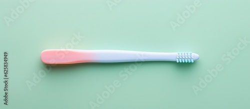 Photo of a pink and white toothbrush on a green surface with copy space with copy space