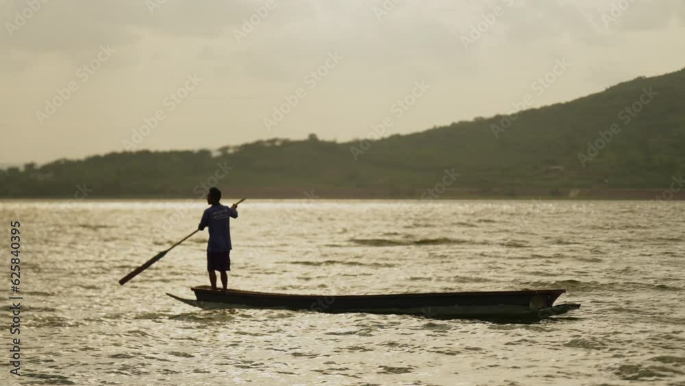 Silhouette of fishermen alone in a boat reeling up a fishing pole in a sunset lake,man recreation with fishing rod outdoor catching lifestyle fish at sunset