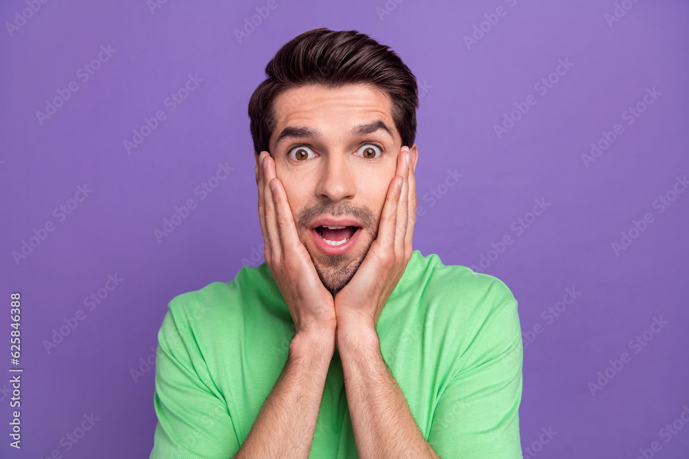 Photo of funny young guy touch cheekbones surprised impressed reaction wear trendy t-shirt unexpected news isolated on purple background Photo of funny young guy touch cheekbones surprised impressed reaction wear trendy t-shirt unexpected news isolated on purple background