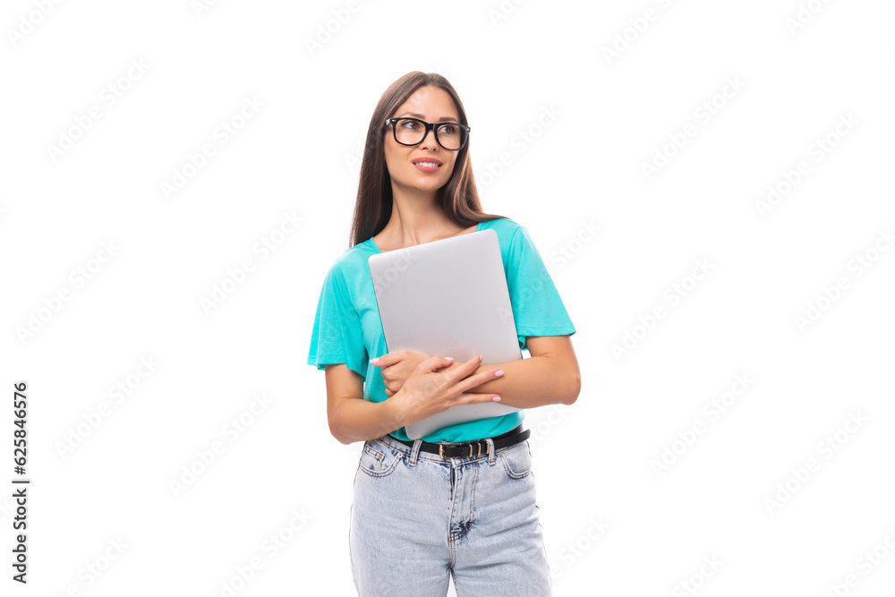 young attractive european woman with black long hair dressed in a blue t-shirt is studying remotely using a laptop young attractive european woman with black long hair dressed in a blue t-shirt is studying remotely using a laptop