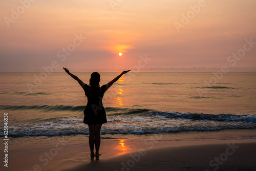 Silhouettes  of Woman raise hands up to the sunset sky  praise and worship God against the sun  at the beach with copy space for your text, Christian praise and worship concept  © isara