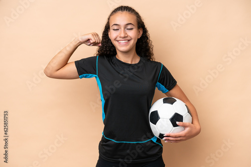 Young football player woman isolated on beige background doing strong gesture © luismolinero