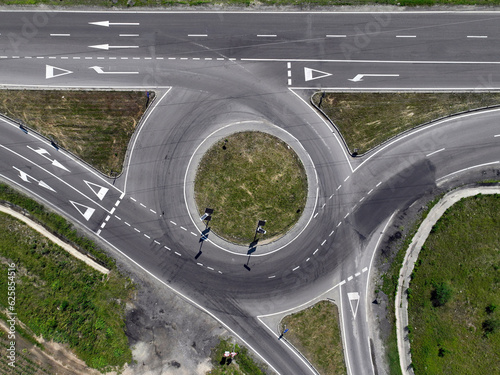 An aerial overview of an empty roundabout situated on an urban street, revealing the circular central island and the arrangement of entry and exit lanes. photo