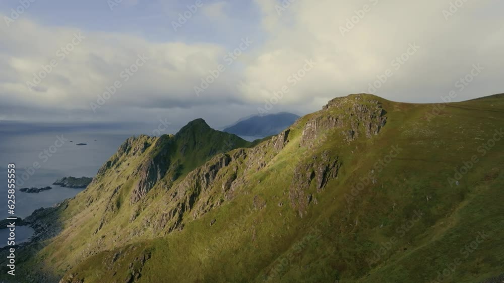 Drone flies over a backpacker man standing on top of a cliff toward the epic landscapes of the Lofoten Islands Drone flies over a backpacker man standing on top of a cliff toward the epic landscapes of the Lofoten Islands