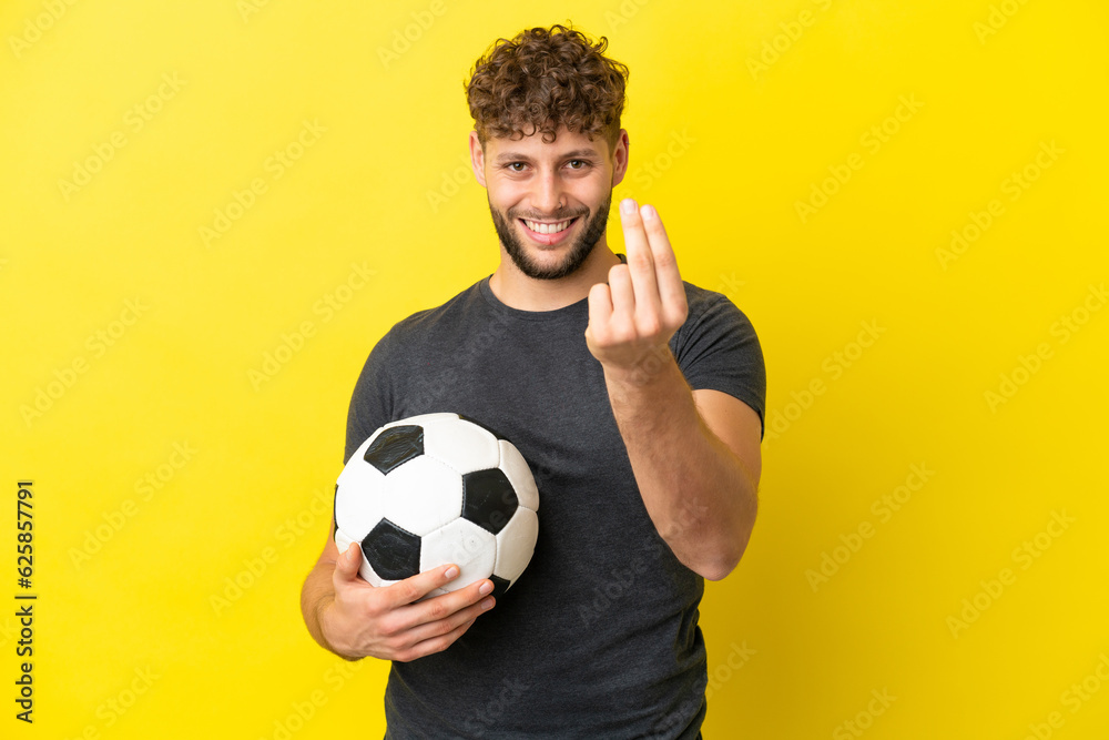 Handsome young football player man isolated on yellow background making money gesture Handsome young football player man isolated on yellow background making money gesture