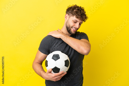Handsome young football player man isolated on yellow background suffering from pain in shoulder for having made an effort