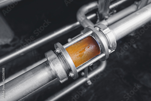 Brewing equipment for quality control, sight glass full of golden beer on stainless steel pipe. Concept brewery industry photo