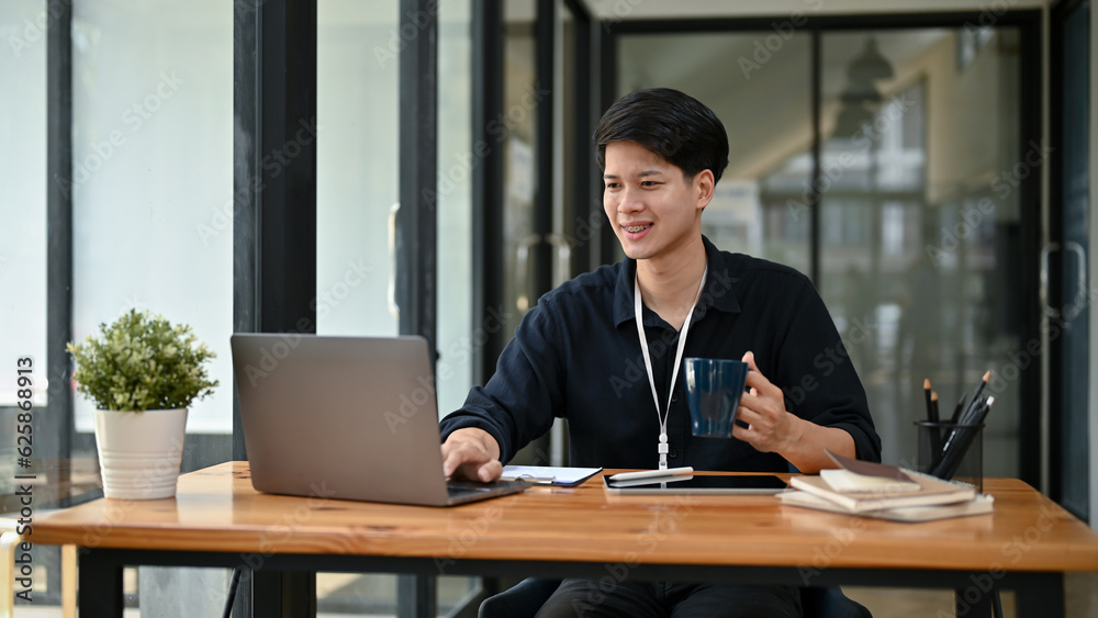 A happy asian businessman or male office worker working on his work on his laptop A happy asian businessman or male office worker working on his work on his laptop