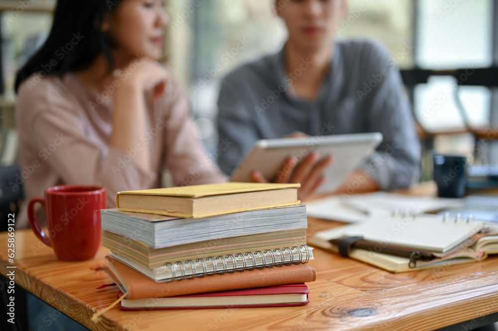 Close-up image of a stack of books and stationery on a table in a campus library Close-up image of a stack of books and stationery on a table in a campus library