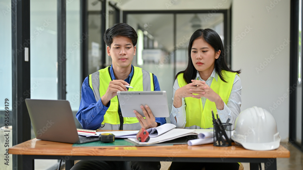 Two professional and serious Asian engineers are discussing work, and working on a project together.