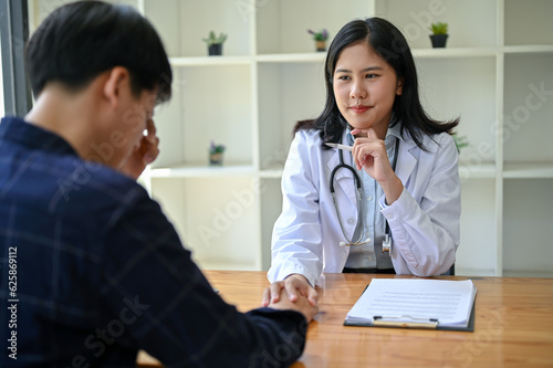 A doctor is touching a patient's hand to provide comfort and reassurance during the medical checkup