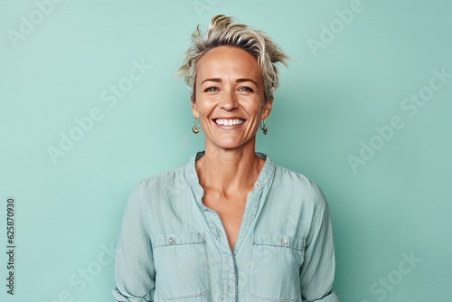 Portrait of a smiling middle-aged woman standing against turquoise background photo