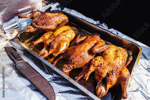 Roasted ducks on a metal baking sheet. Cooking poultry meat on fire and coals. A hunter's trophy with a golden crust. Close-up.