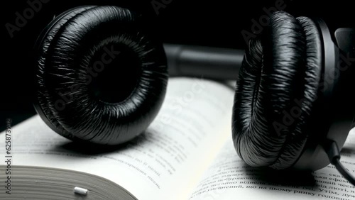 Book and black headphones on black background. Audio book concept. Relax and leisure