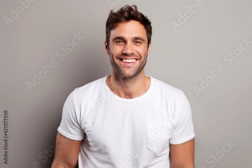 Portrait of a smiling young man looking at camera and standing against grey background