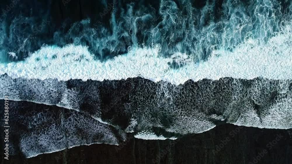 Big Waves rolling from above. Top down 4k drone view on blue turquoise ocean, breaking waves, whitewash. Sunny day over the sea. Huge swell hitting shoreline.