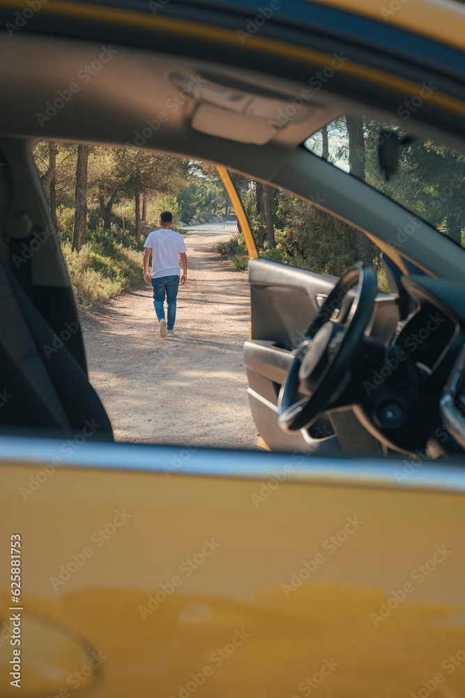 Fototapeta premium Latino man getting out of a vehicle on a forest road