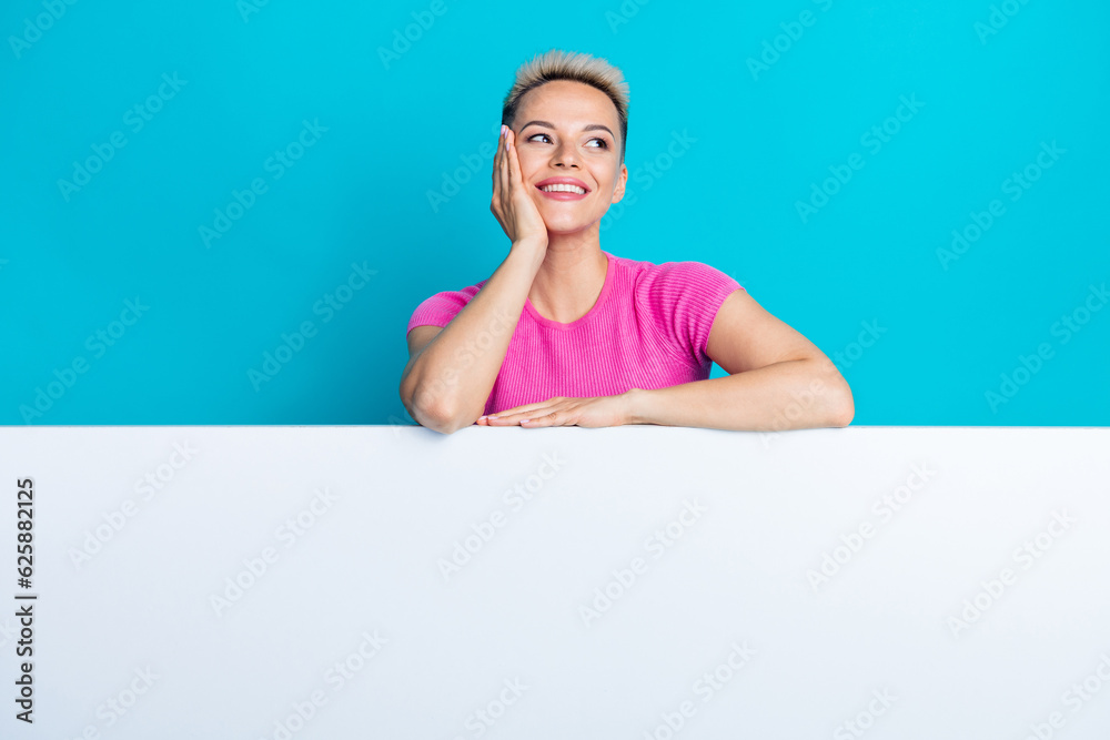 Portrait of gorgeous lovely woman with stylish hairstyle wear pink top look empty space palm on chin isolated on blue color background Portrait of gorgeous lovely woman with stylish hairstyle wear pink top look empty space palm on chin isolated on blue color background