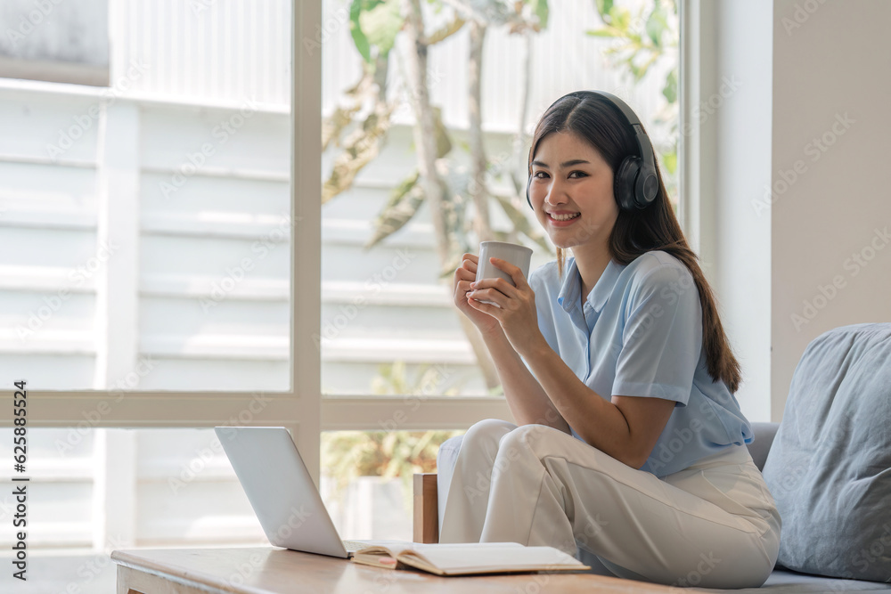 Young woman relaxing and drinking cup of hot coffee or tea using laptop computer. woman checking social apps and working. Communication and technology concept Young woman relaxing and drinking cup of hot coffee or tea using laptop computer. woman checking social apps and working. Communication and technology concept