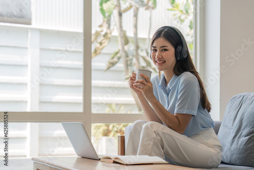 Young woman relaxing and drinking cup of hot coffee or tea using laptop computer. woman checking social apps and working. Communication and technology concept