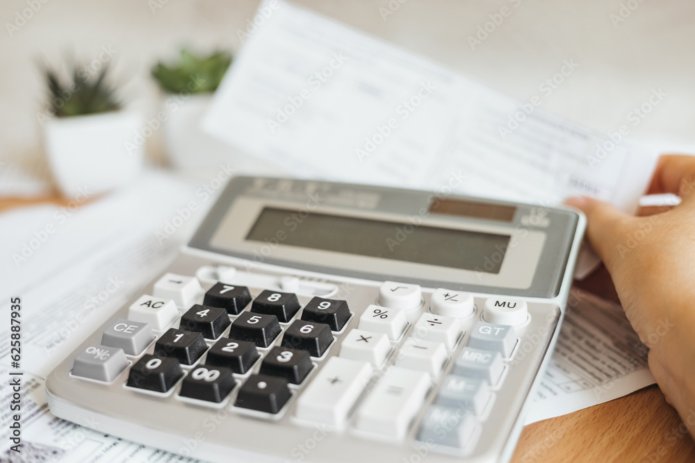payment of utility bills, female hands and a calculator close up with papers invoices cheque bills payment of utility bills, female hands and a calculator close up with papers invoices cheque bills